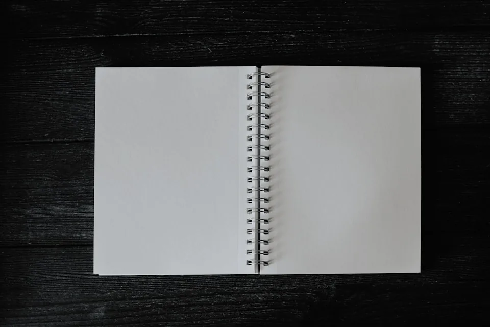 Les pages blanches d'un carnet à spirale ouvert sur une table.